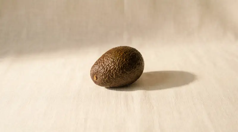Sade krem fon önünde avokado; bebeğin bu haftaki yaklaşık boyutu.